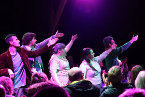 5 Orpheus students stood in front of each other, performing to an audience in the Orpheus Barn theatre