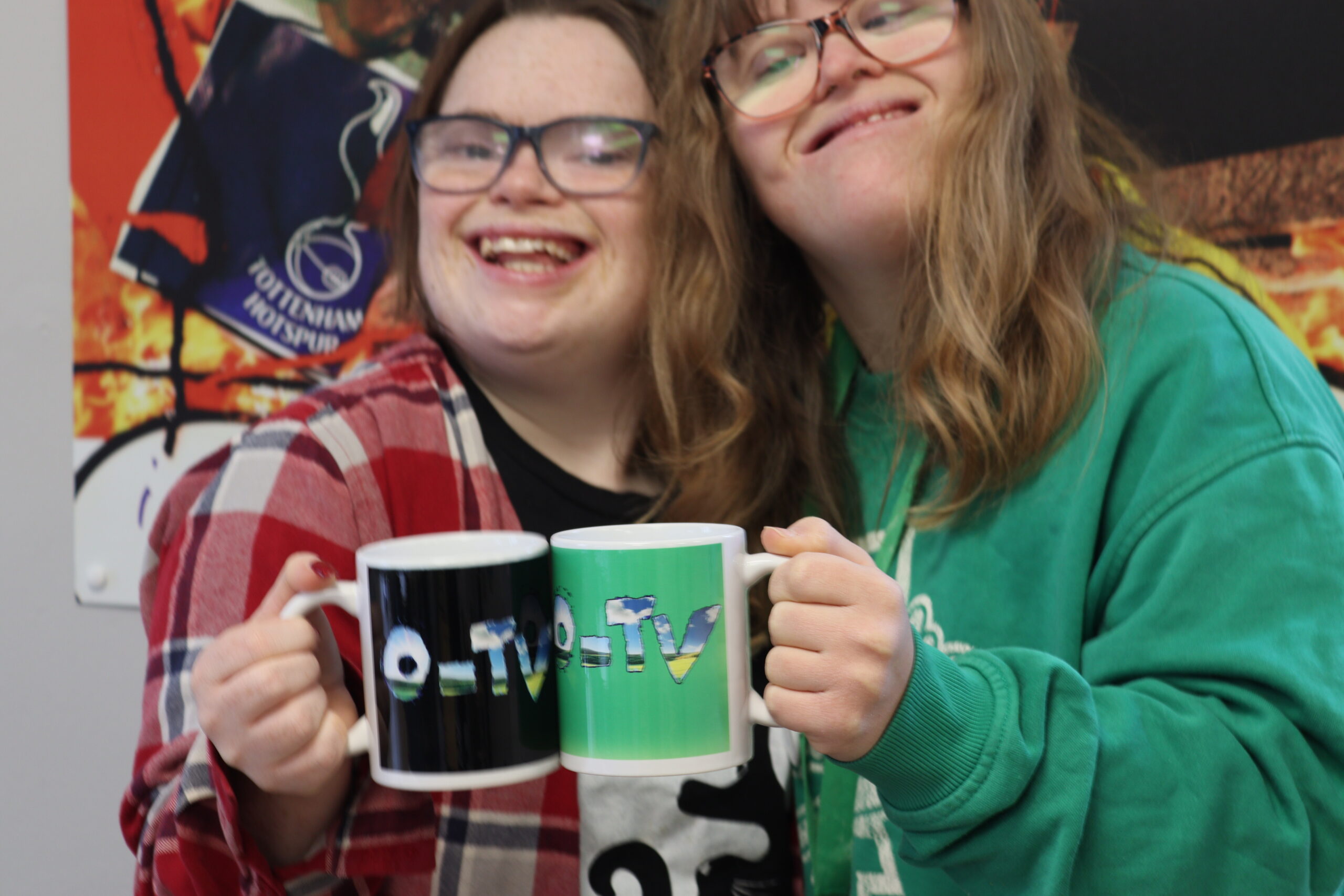 Two students smiling to the camera toasting their O-TV mugs